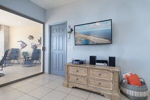 A living room with a large TV, a wooden dresser, and a wicker basket.