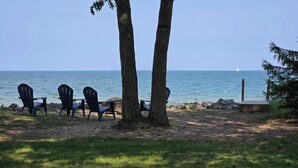 A beach setting with four Adirondack chairs, a wooden deck, and a view of the ocean. - Private beach location (Oscoda)