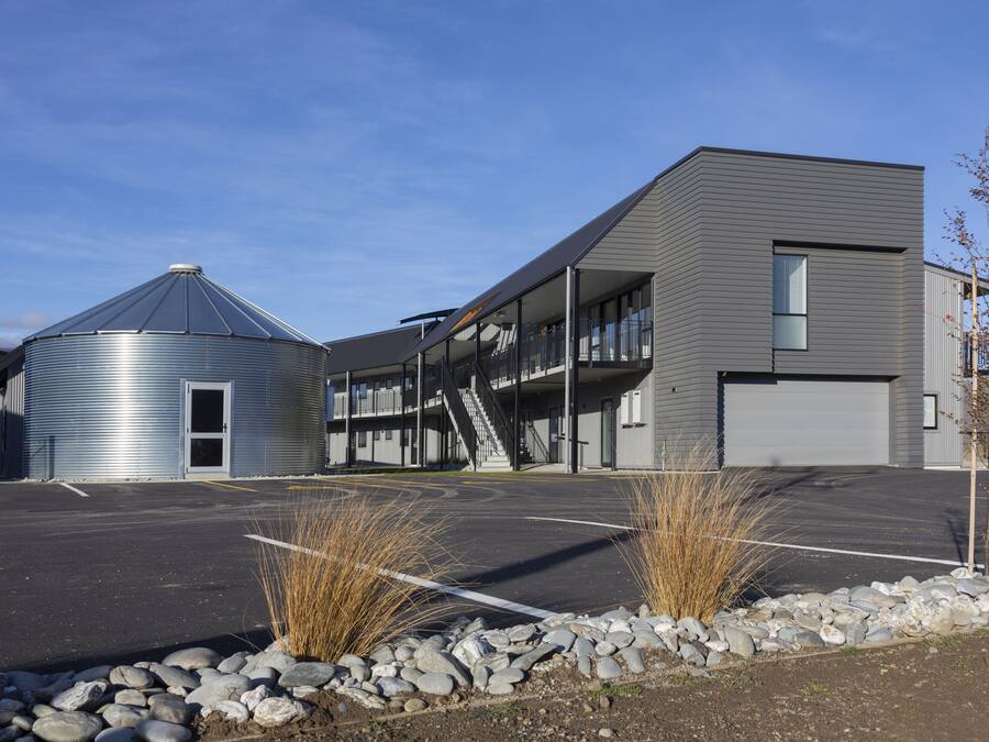 A modern building with a silo, a covered outdoor area, and a parking lot.