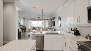 A modern kitchen with white cabinetry, a stainless steel dishwasher, and an island with a sink.