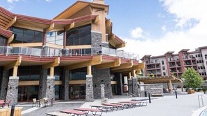 A multi-story hotel with a prominent entrance, outdoor seating, and a clear sky. - Pools open May long weekend!  Holiday Time @ West Kelowna's hidden gem!  2BR (West Kelowna)