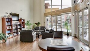 A spacious living room with a large window, a fireplace, and a bookshelf. - Pools open May long weekend!  Holiday Time @ West Kelowna's hidden gem!  2BR (West Kelowna)