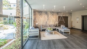 A modern lobby with a stone accent wall, a sofa, a coffee table, and a reception desk. - Parc Du Cap 2 bedroom apartment VRBO (Antibes)