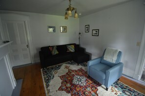 A living room with a black sofa, a blue armchair, and a patterned rug.
