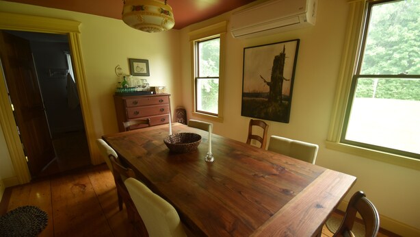 A wooden dining table with chairs, a chandelier, a window with a view of trees, and a painting on the wall. - Relax at the historic Austin House (Addison)