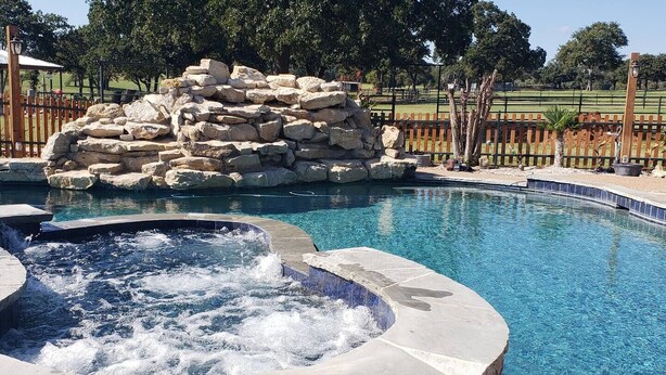 A swimming pool with a hot tub and a rock feature. - Barn Loft at Private Retreat - Horses Welcome (Boyd)