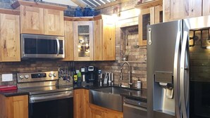 A modern kitchen with wooden cabinets, stainless steel appliances, and a brick backsplash. - Barn Loft at Private Retreat - Horses Welcome (Boyd)