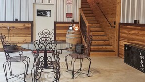 A cozy indoor setting with a wooden staircase, a round table with metal chairs, and a bar area with a barrel and a sign indicating adult supervision for children. - Barn Loft at Private Retreat - Horses Welcome (Boyd)