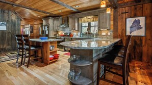 A spacious kitchen with wooden cabinets, a granite countertop island, and modern appliances. - Bishop | Amazing location on Rangeley Lake and close to downtown (Rangeley)