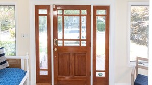 Amplia habitación con un gran ventanal de arco, una puerta de madera con paneles de vidrio y un ventilador de techo.