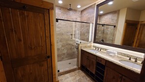 A bathroom with a wooden door, a shower area with a glass door, a large mirror, and a vanity with a sink. - Gatlinburg Resort Getaway (Gatlinburg)