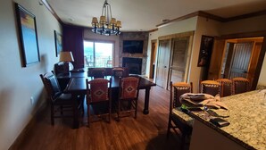 A dining area with a wooden table and chairs, a chandelier, and a fireplace. - Gatlinburg Resort Getaway (Gatlinburg)