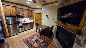 A kitchen with wooden cabinets, stainless steel appliances, a dining table with chairs, a fireplace, and a television mounted above it. - Gatlinburg Resort Getaway (Gatlinburg)