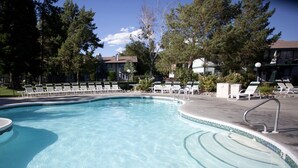 A clear swimming pool with lounge chairs and a tiled deck.