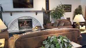 A cozy living room with a fireplace, comfortable seating, and a table with a plant.