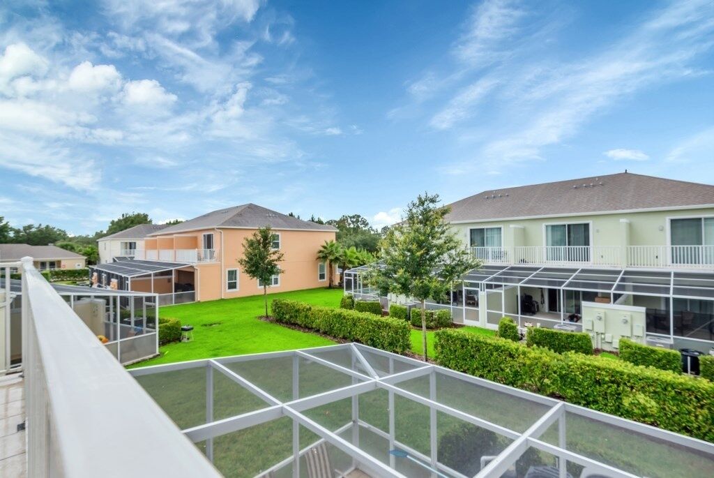 A residential area with modern houses, a green lawn, and a glass-enclosed balcony.