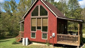 A red wooden cabin with a gabled roof, large windows, and a wooden deck. - 540-acre farm with trails, creeks, animals & nearby attractions (Irvine)