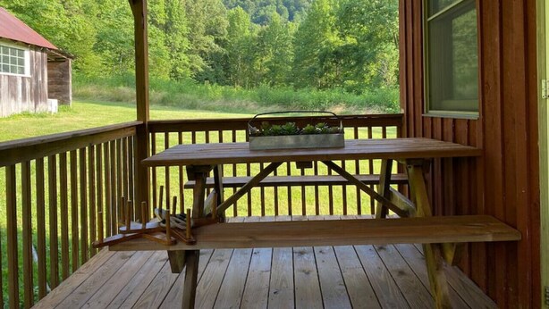 A wooden deck with a picnic table and a planter box, overlooking a forested area. - 540-acre farm with trails, creeks, animals & nearby attractions (Irvine)