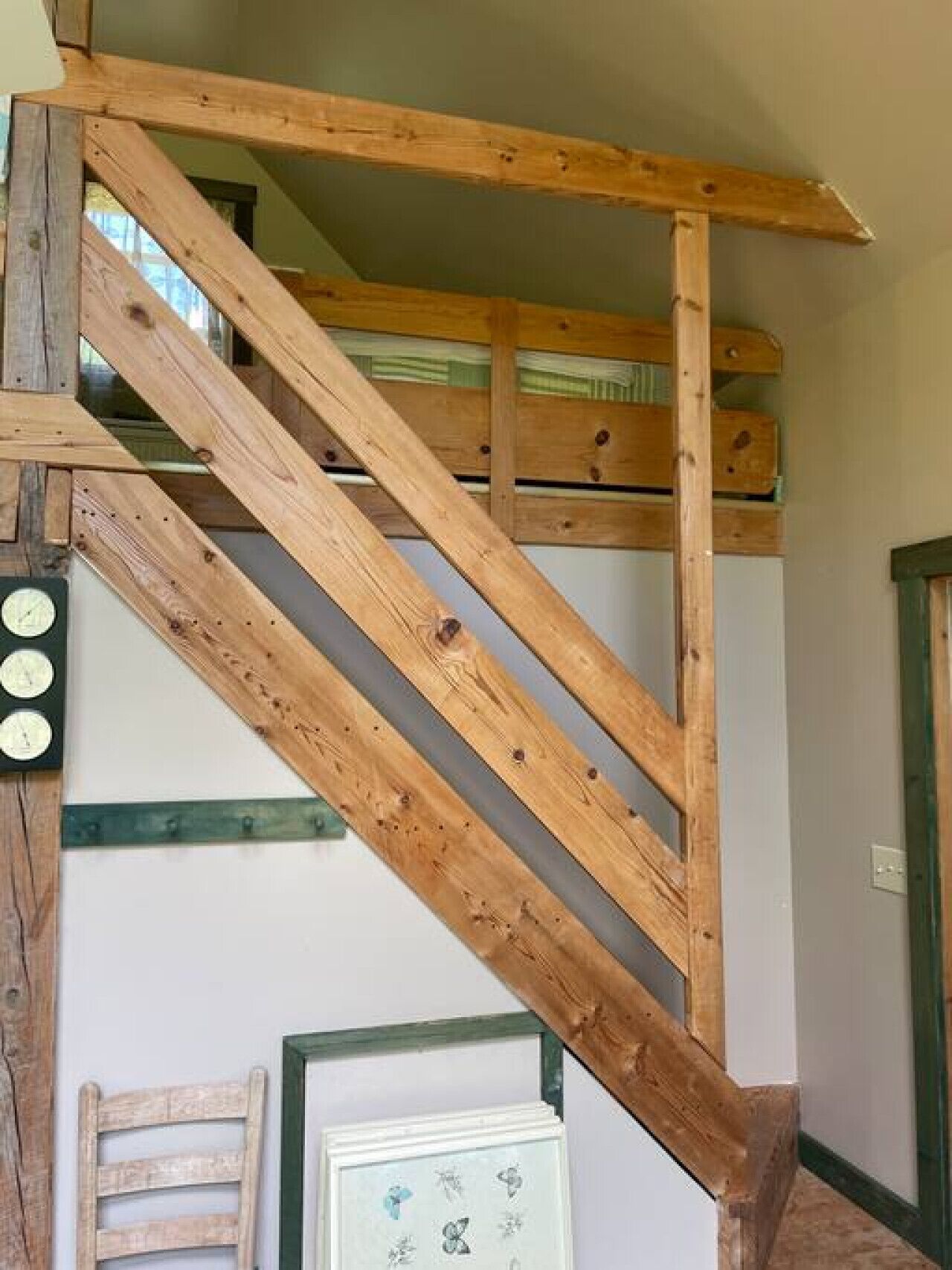 Eine Holztreppe mit schlichtem Design, eine Uhr und ein gerahmtes Bild an der Wand.