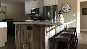 A kitchen with a central island, white cabinets, stainless steel appliances, and a clock on the wall.