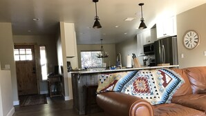 A spacious kitchen with a central island, wooden flooring, and pendant lighting.
