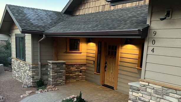 A modern house with a stone facade, a stone fireplace, and a paved driveway.
