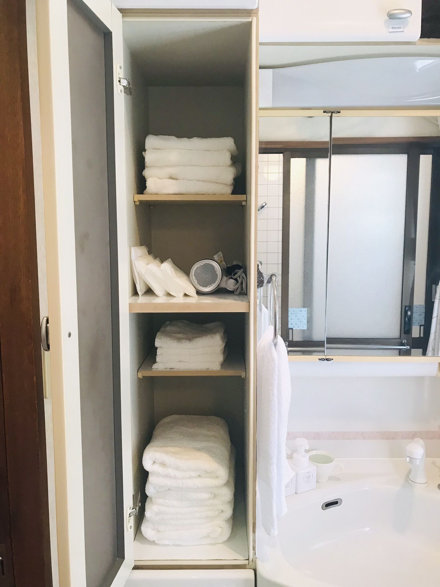 Un baño con un lavamanos blanco, un espejo y un perchero para toallas.