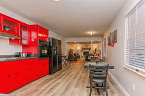 Une cuisine moderne avec des meubles rouges et un coin repas comprenant une table et des chaises.
