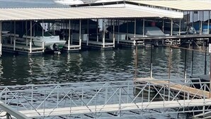 Un port de plaisance avec des bateaux amarrés, un bâtiment jaune et une structure verte en arrière-plan.