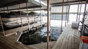 Un quai abrité avec une terrasse en bois, une petite piscine et un espace couvert où se trouve un bateau.