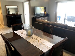 Relax in this stylish living room with a large TV, comfortable sofa, and dining area.