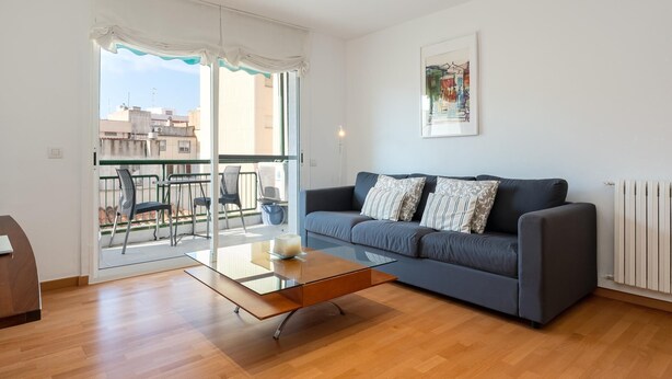 A modern living room with a glass coffee table, grey sofa, and a balcony with chairs. - Spacious apartment with A/C and heating (L'Ametlla de Mar)