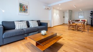 A modern living room with a grey sofa, a glass coffee table, and a wooden dining table with chairs. - Spacious apartment with A/C and heating (L'Ametlla de Mar)