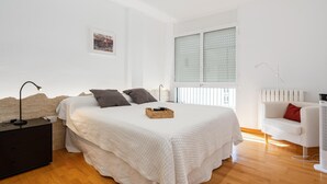A bedroom with a bed, bedside table, lamp, and a window with blinds. - Spacious apartment with A/C and heating (L'Ametlla de Mar)