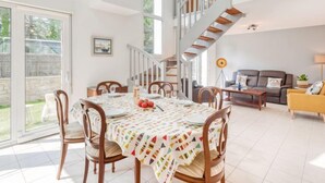 A spacious living area with a dining table set for four, a staircase, and a sofa in the background. - Armorique by Interhome (Carnac)