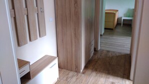 A hallway with wooden flooring, a wardrobe with multiple doors, and a small desk with drawers. - Lower vacation apartment between Tauber Valley, Odenwald and Bauland (Ahorn)