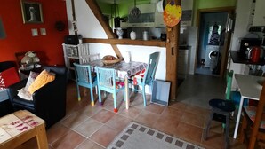Un vaste salon comprenant un coin repas, une cuisine et un escalier menant à un autre niveau.