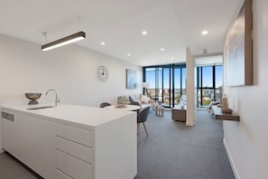 Uma cozinha moderna com uma ilha central, sala de jantar com mesa e cadeiras, e área de estar com sofá e mesa de centro.