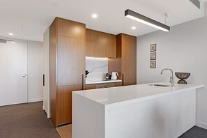 A modern kitchen with a large island, wooden cabinets, and a white countertop.