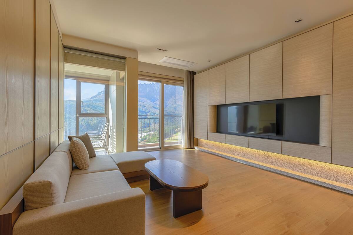 A modern living room with a sofa, a coffee table, and a TV mounted on the wall.