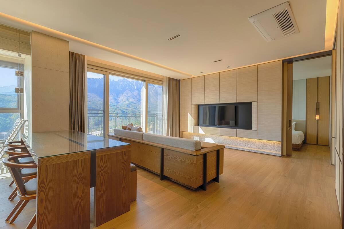 A modern kitchen with a large island, wooden cabinets, and a built-in TV.