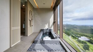 Ein moderner Wellnessbereich mit Whirlpool, Handtuchhalter und Blick auf eine üppige Landschaft.