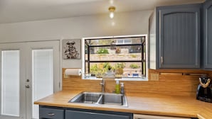 A kitchen with a wooden countertop, a double sink, and a window overlooking a garden. - Bay views, easy access to beaches and downtown. Relax in your own hot tub!!! (San Diego)