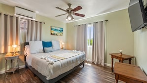 A bedroom with a bed, a ceiling fan, a nightstand, a table, and a TV. - Bay views, easy access to beaches and downtown. Relax in your own hot tub!!! (San Diego)