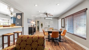 A modern kitchen with a bar area, wooden flooring, and a dining area with a table and chairs. - Bay views, easy access to beaches and downtown. Relax in your own hot tub!!! (San Diego)