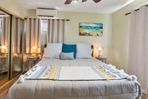 A neatly arranged bedroom with a large bed, two bedside tables with lamps, a painting on the wall, and a ceiling fan. - Bay views, easy access to beaches and downtown. Relax in your own hot tub!!! (San Diego)
