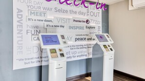 Een hotel receptie met een muur vol inspirerende citaten en twee zelfbedieningskiosken.