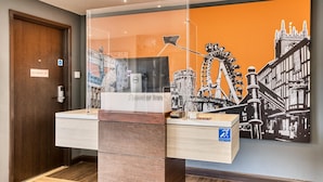 Een receptiebalie met een stadsgezichtsmural, een bord met de tekst 'Alleen voor medewerkers' en een bord met 'Premier Inn'.