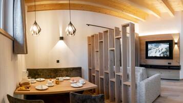 Un comedor con una mesa de madera, sillas y un televisor montado en la pared.
