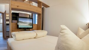 Ett sovrum med en säng, en tv som är monterad på en vägg av trä och ett fönster.